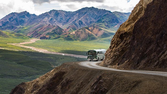 a bus comes around a mountainside on a winding dirt road