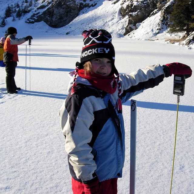 a young visitor makes scientific field measurements in the snow