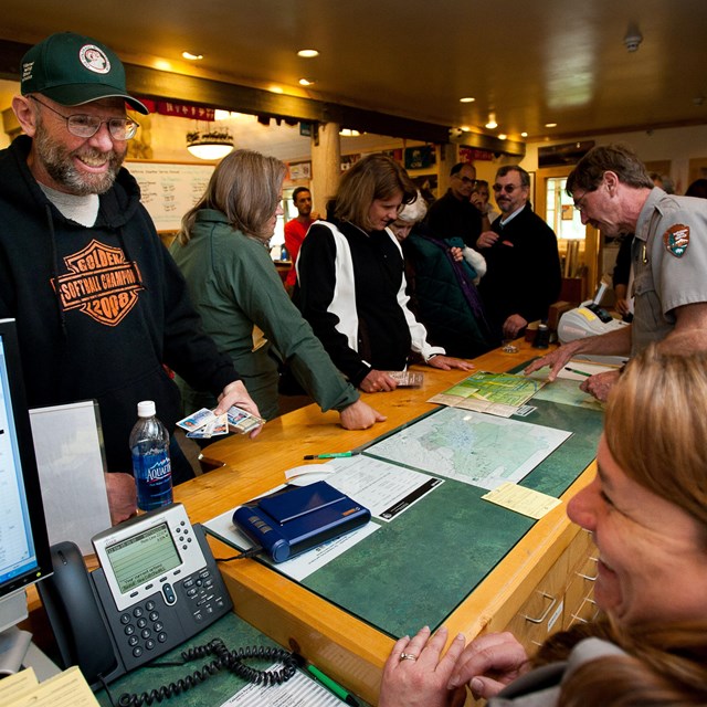 two rangers behind a desk speaking to many other people