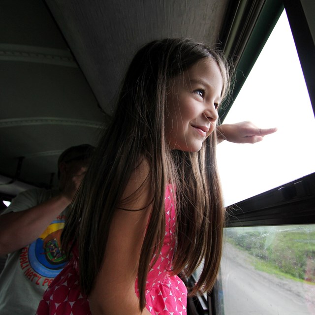 a young girl looks out the window of a bus