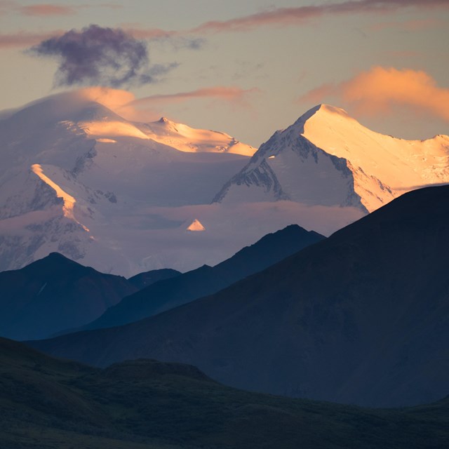 a huge snowy mountain tinged pink by setting sun