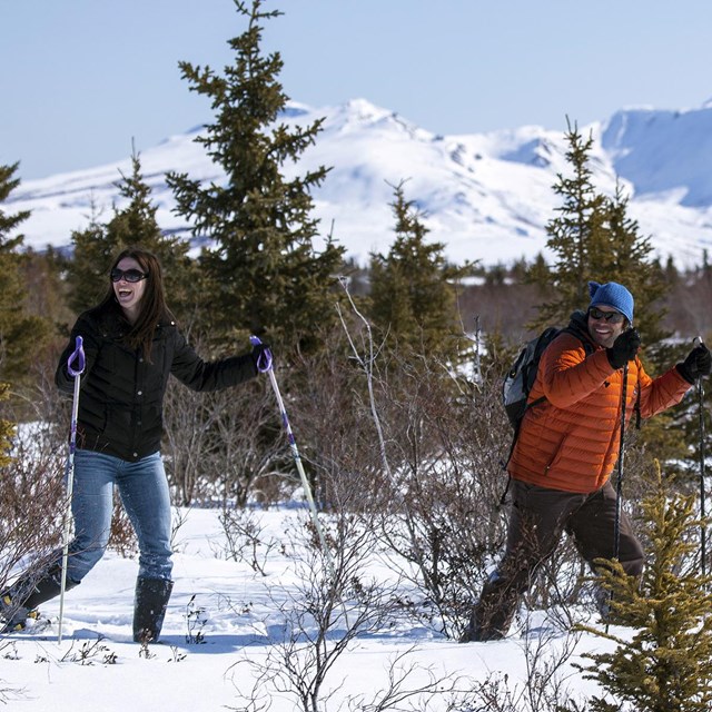 a man and woman hike using snowshoes
