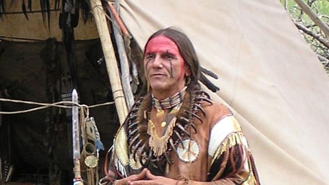 An American Indian speaking outside a replica tipi