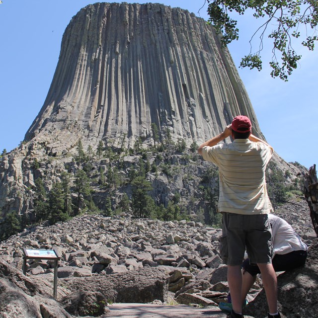 man with binoculars in foreground, Devils Tower in background