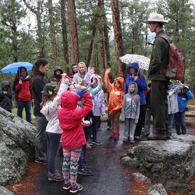 A ranger addressing a group of students on a park trail.