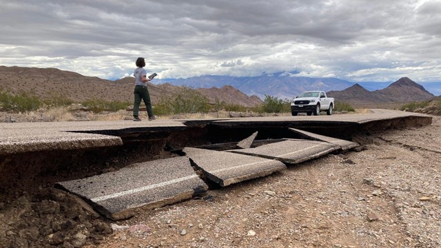 A park ranger walking across a damaged section of Daylight Pass in Death Valley National Park