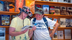 two women look at books with shelves behind them