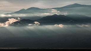 Dark mountains draped in ominous clouds at sunrise.