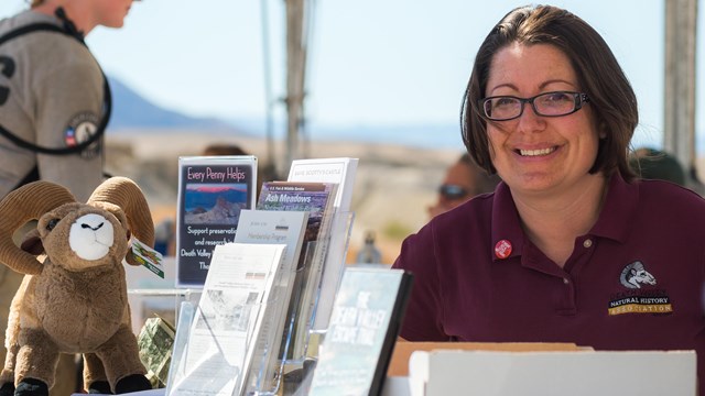 A smiling woman at a fair booth for the Death Valley Natural History association