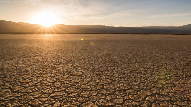 a dry lake bed in front of the setting sun