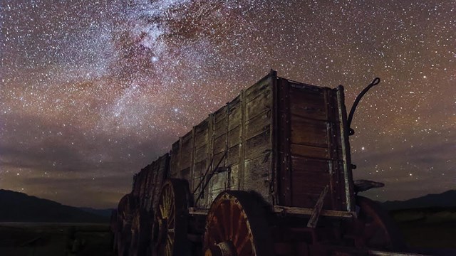 Milky way in dark blue sky over Harmony Borax Works wooden 20 Mule Team Wagon.