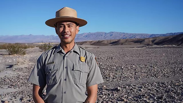 Ranger in uniform smiling at camera against blue sky.