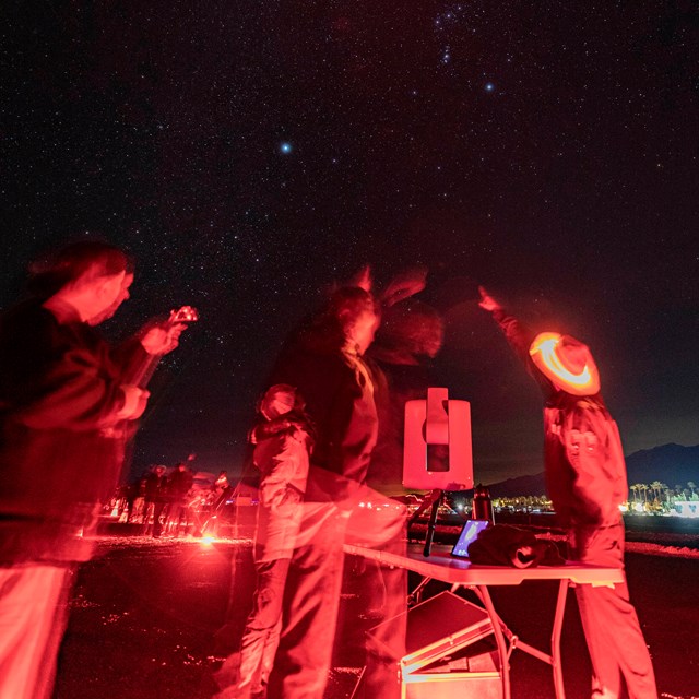 Uniformed ranger pointing to different areas in the night sky for visitors.