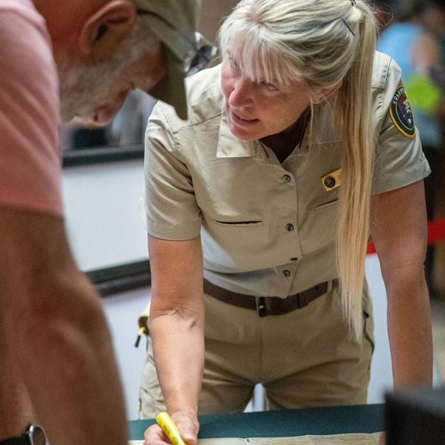 A woman with blonde hair, wearing a tan colored uniform with the National Park Service Volunteers