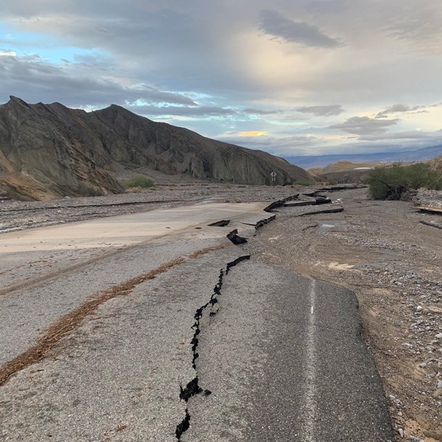 A mountain landscape outlines a stretch of road destroyed by flood waters.