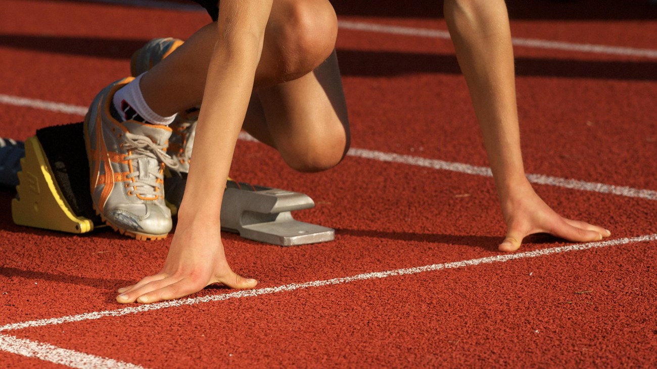 Hands and feet of sprinter at a starting line.