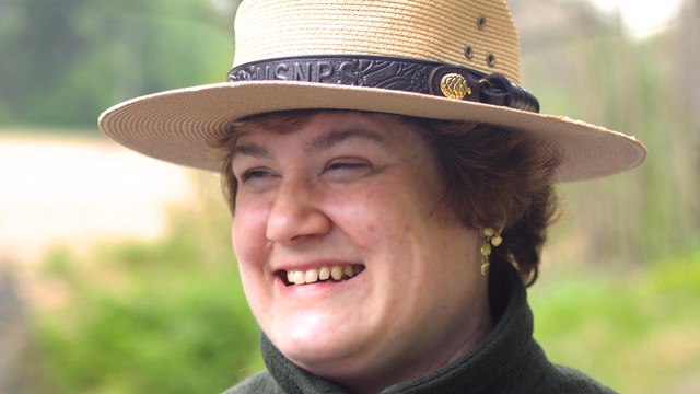 A smiling ranger wears her traditional Campaign or "Flat Hat".