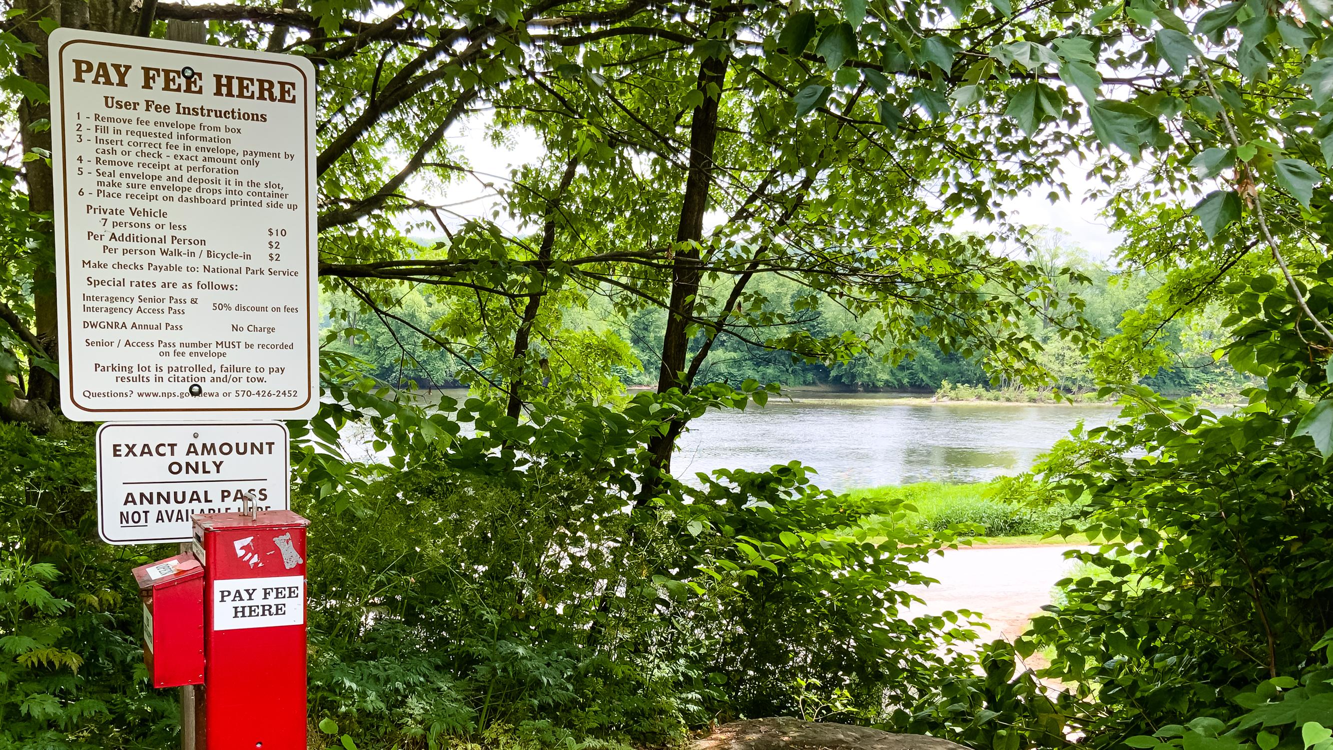 An Iron Ranger fee box sits on the left while off to the right is the Delaware river