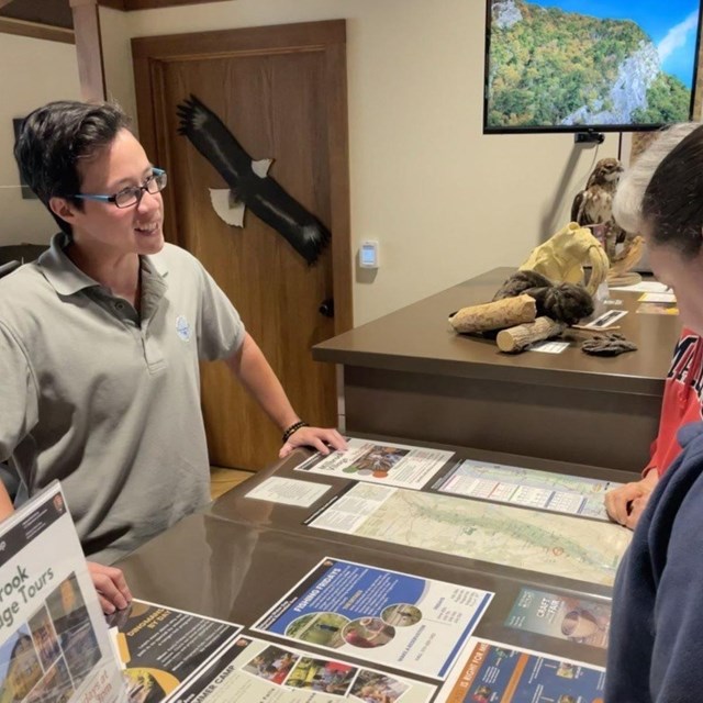 A teacher Ranger teacher helps visitors at an information desk.