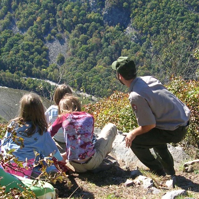 A park ranger and a group of students look out on a view from Mount Minsi.