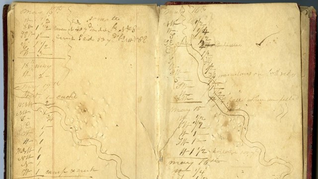 A photo of a weathered diary with drawings and notes scrawled across both pages.