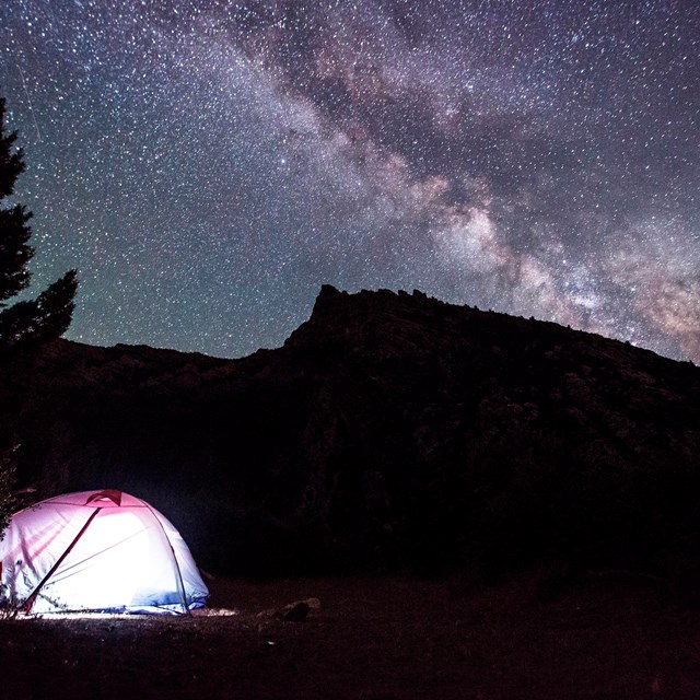 lighted tent underneath a starr filled night sky