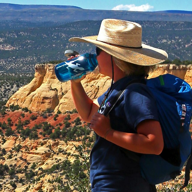Woman wearing a hat drinking water from a bottle