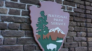 the national park service arrowhead logo on a brick wall
