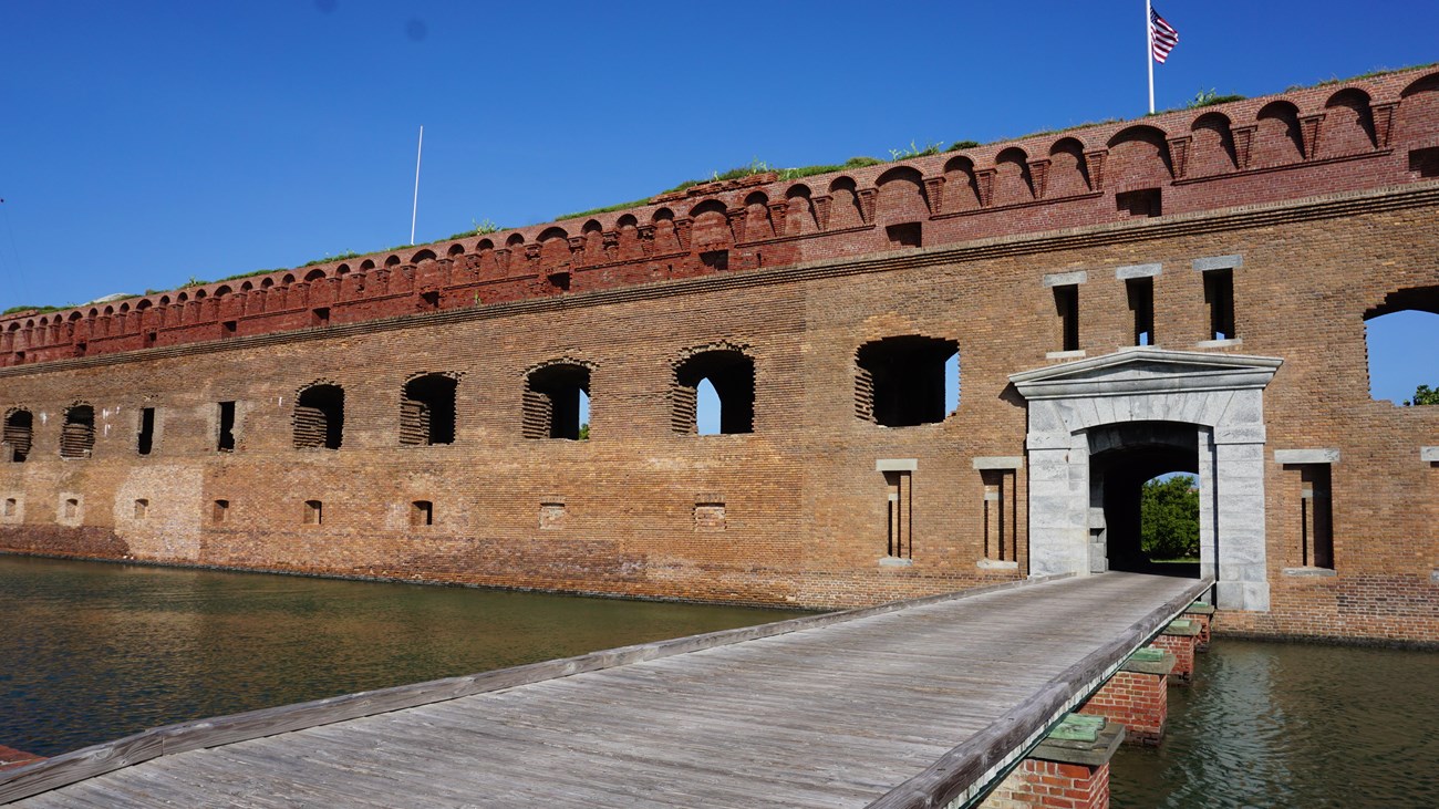 A brick fort and a wooden walkway above water