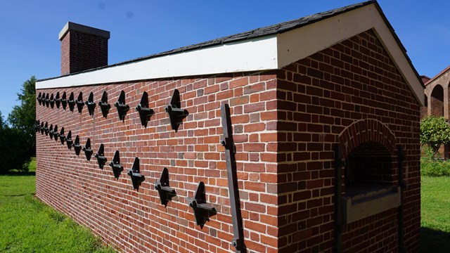 A brick structure with metal attachments, surrounded by grass