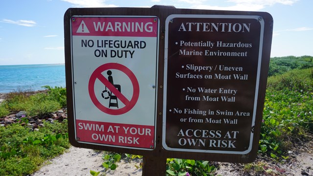 Two signs warning visitors of potential aquatic threats