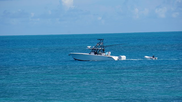 A white boat floating on blue ocean waters with a blue sky in the background