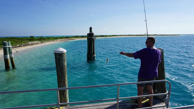 A man fishing on a wooden dock