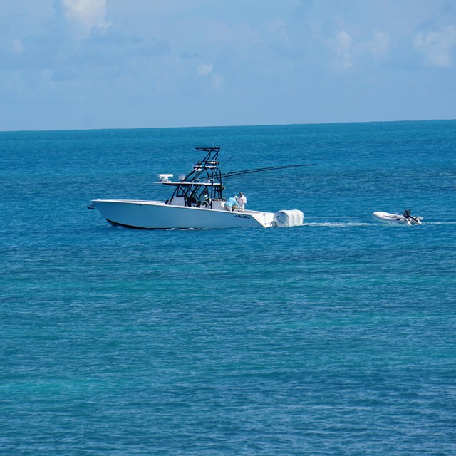 A white boat floating on blue ocean waters with a blue sky in the background