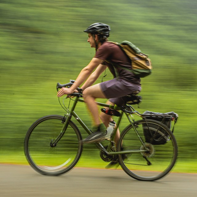 a man wearing a helmet bicycles on a path