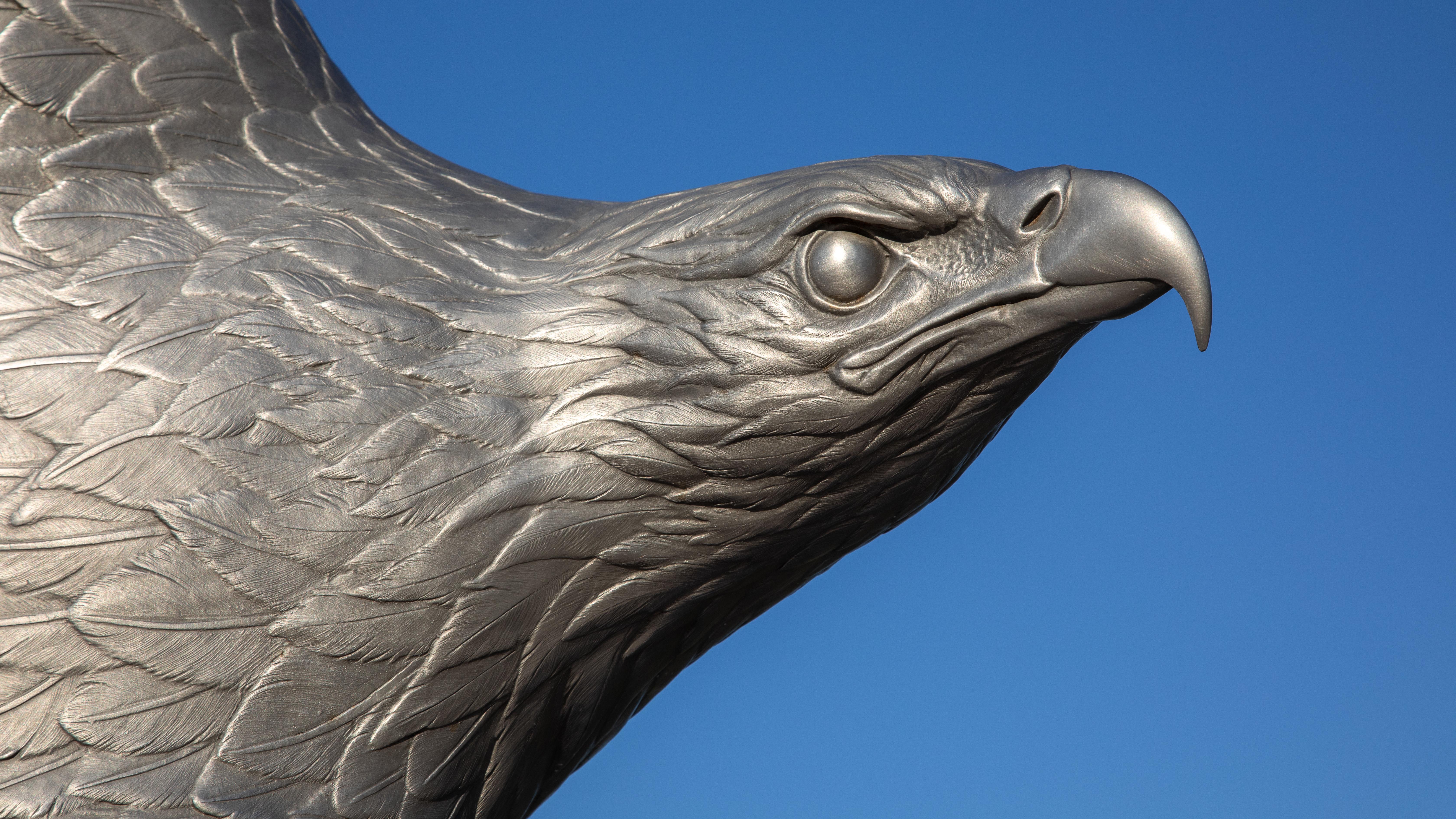 A closeup of a metallic eagle sculpture with fierce-looking face.