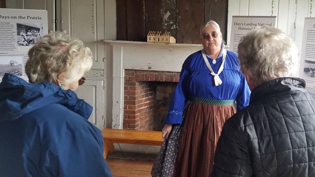 Woman in costume greeting visitors.