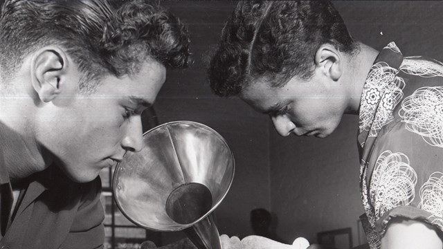 Two young men examining a coin operated phonograph