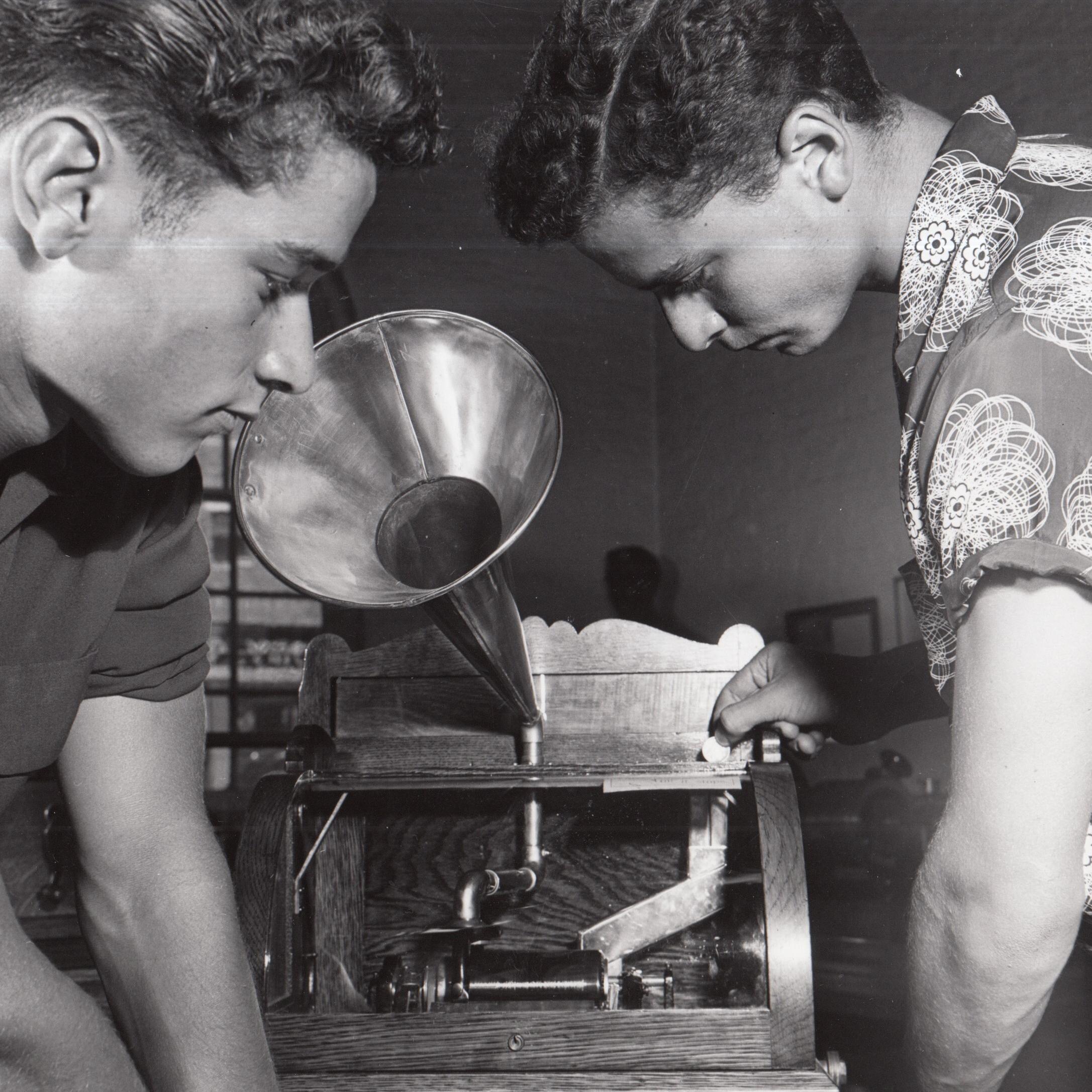 Two young men examining a coin operated phonograph