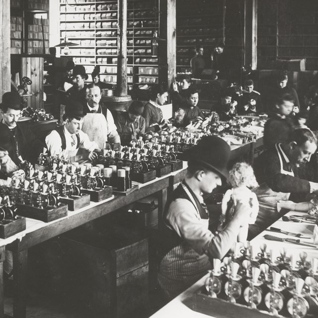 Men and women in a factory around 1888 assembling Thomas Edison's talking dolls.