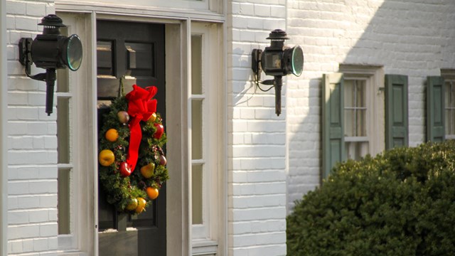 A color image of the black front door of the Eisenhower home with a wreath on it. 