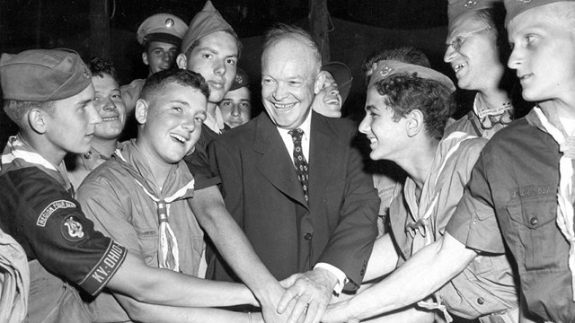 A black and white photograph of boy scouts gathered around Dwight Eisenhower