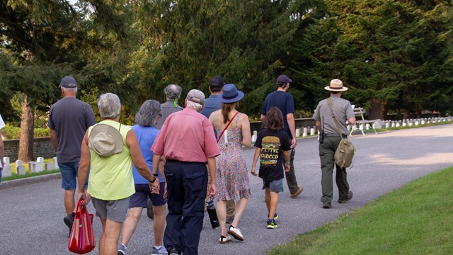 A group of visitors walks through Gettysburg National Cemetery with a park ranger