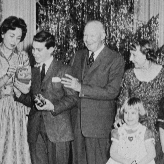 A black and white image of several people gathered together in front of a Christmas tree. 
