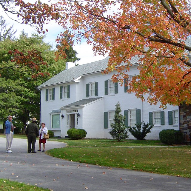 The white brick Eisenhower home with fall foliage in front