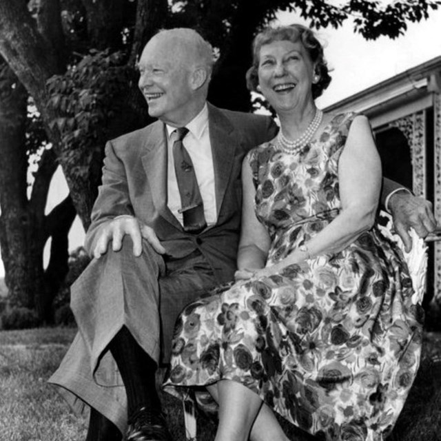A black and white image of Dwight and Mamie Eisenhower seated and smiling