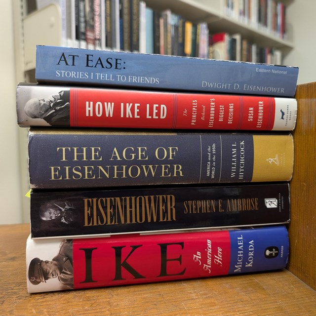A stack of colorful books sits on a brown wood cart
