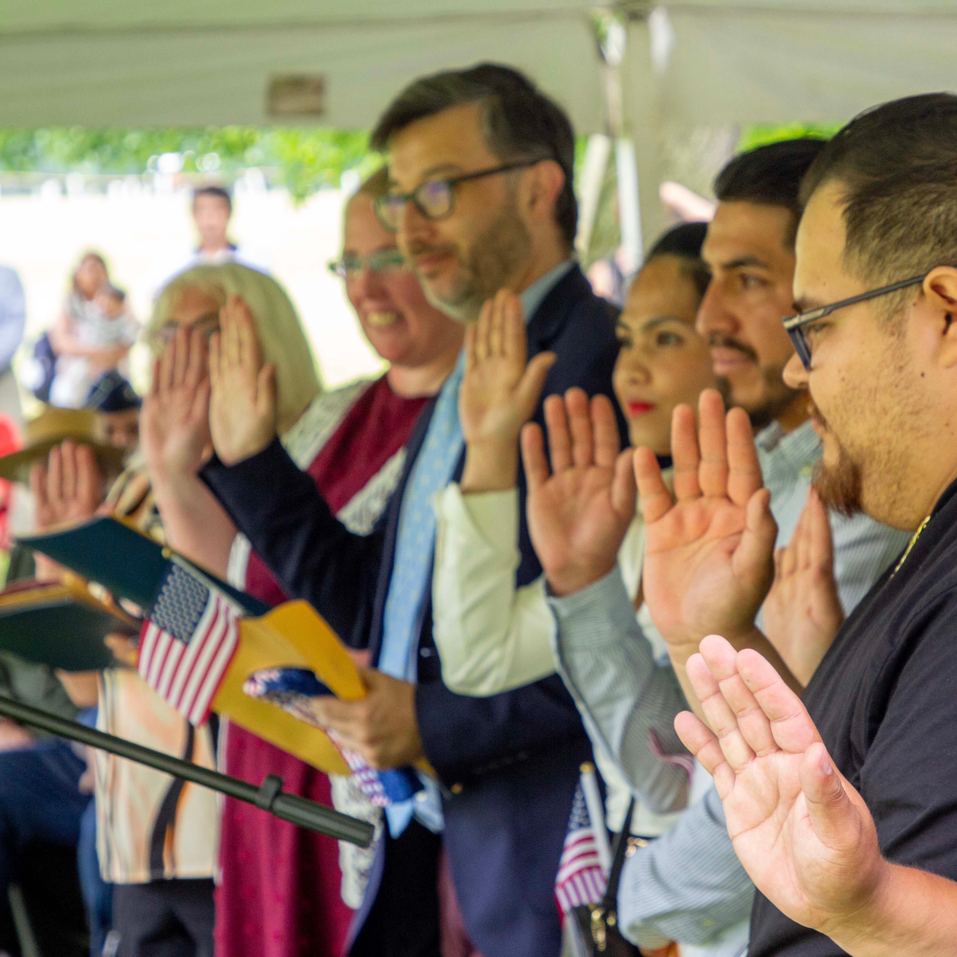 New citizens raise their hands and hold American flags