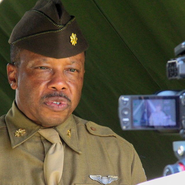 A living historian in WWII uniform speaks to a video camera for a virtual program