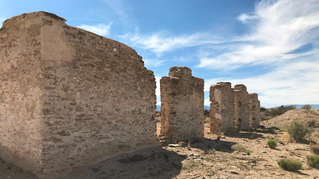 Adobe ruins stand against a stark desert landscape.